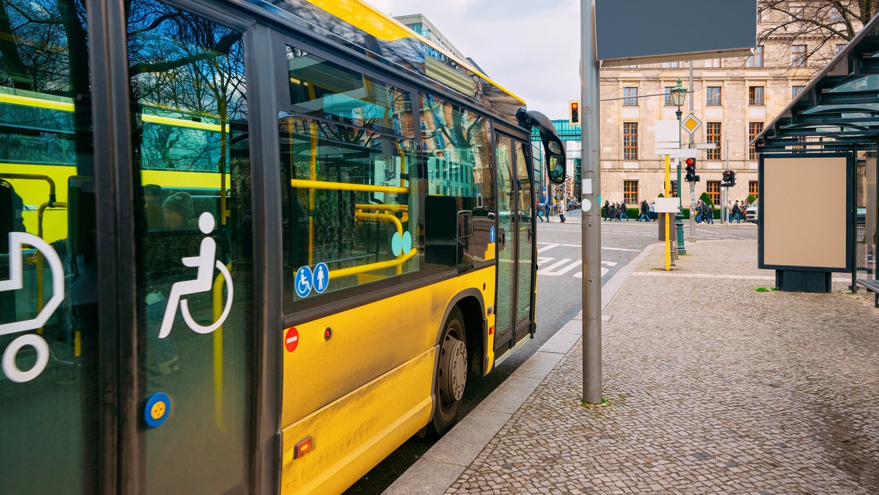 Gelber Bus mit barrierefreiem Einstieg hält an einer Bushaltestelle