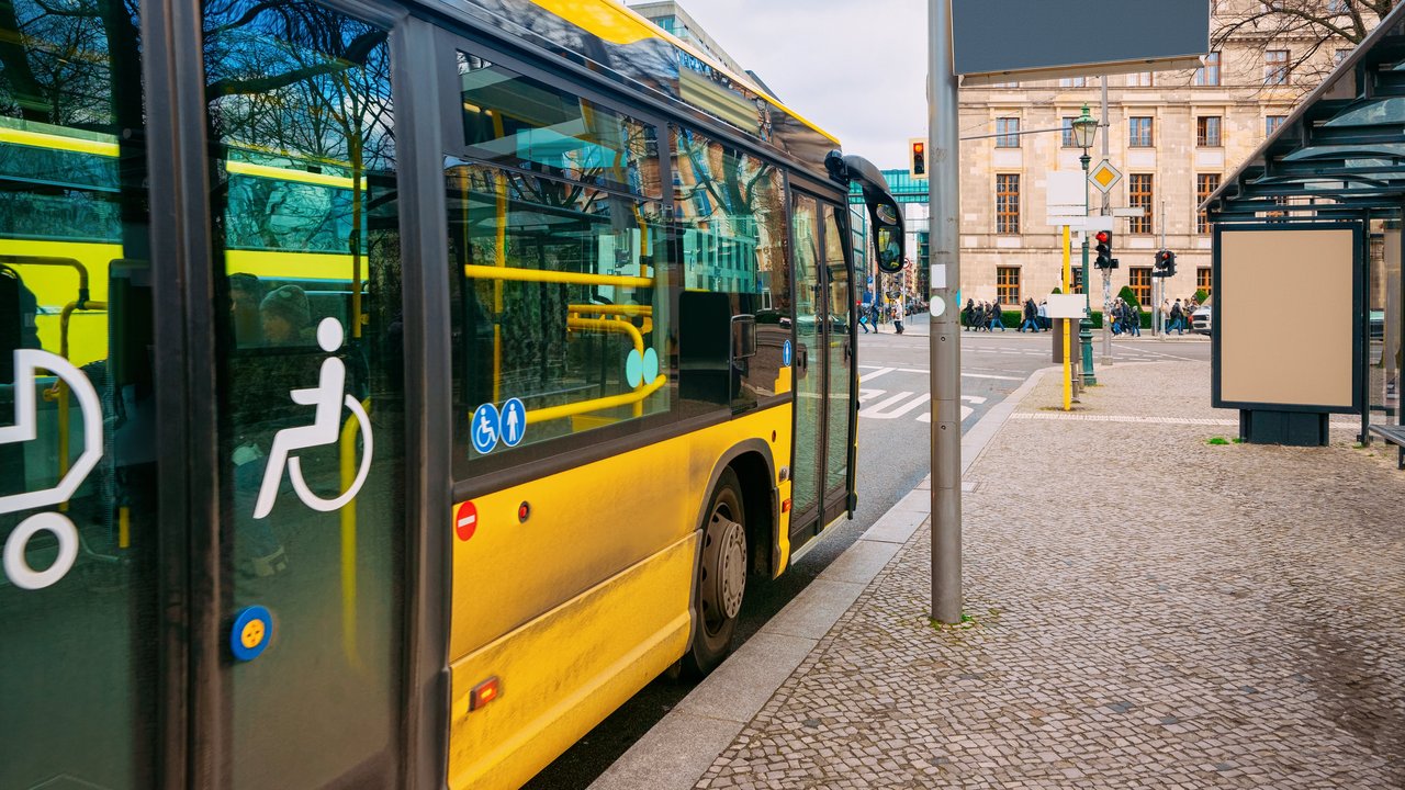Gelber Bus mit barrierefreiem Einstieg hält an einer Bushaltestelle