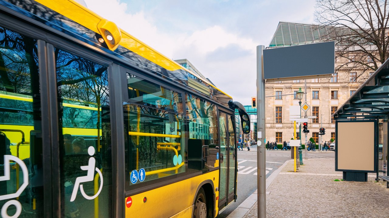 Gelber Bus mit barrierefreiem Einstieg hält an einer Bushaltestelle