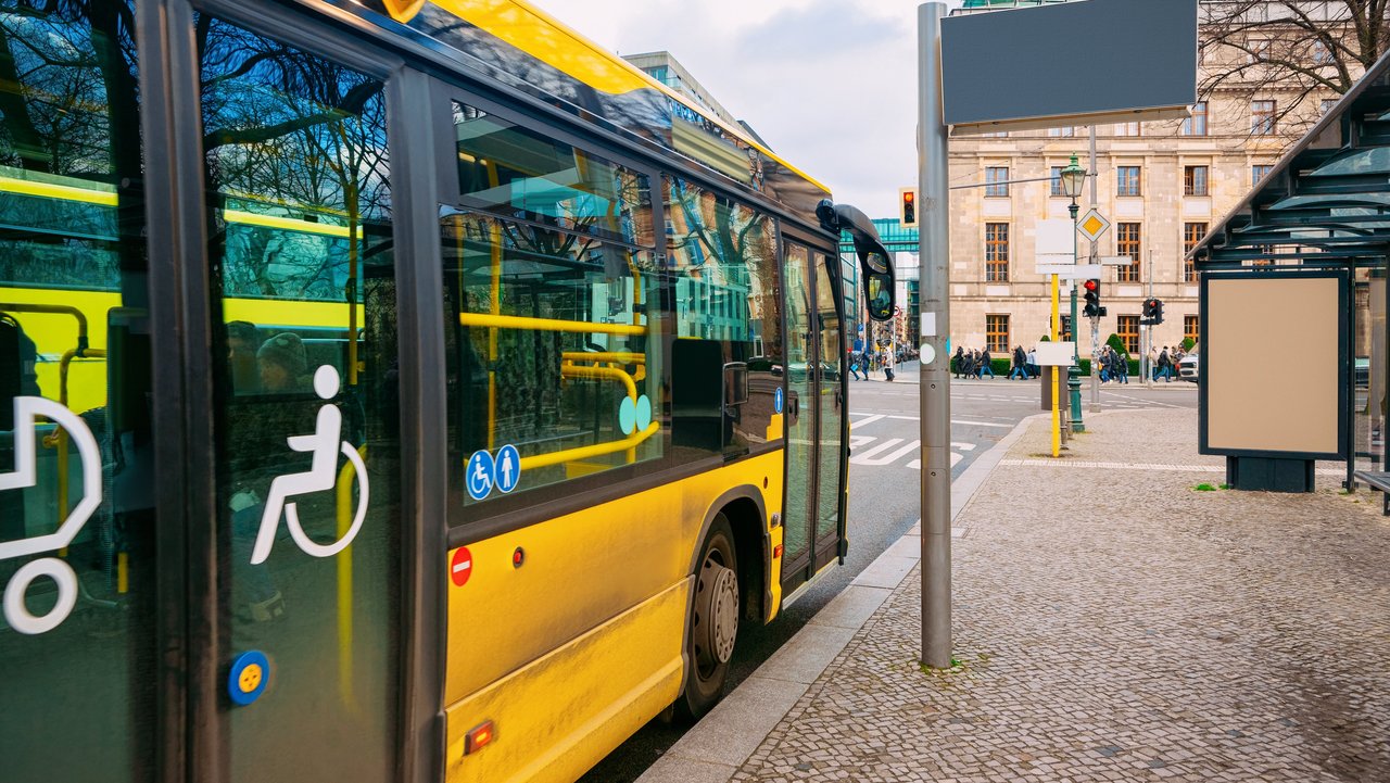 Gelber Bus mit barrierefreiem Einstieg hält an einer Bushaltestelle