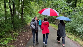 Regierungspräsidentin Bay geht mit Kindern auf einem Waldweg entlang