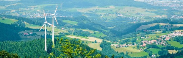 Man blickt von oben auf zwei Windenergieanlagen, die im Wald auf dem Berg Schauinsland stehen.