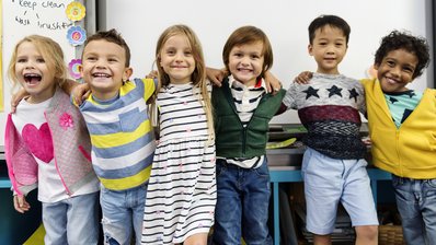 glückliche Grundschulkinder stehen umarmt in Reihe
