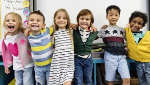 glückliche Grundschulkinder stehen umarmt in Reihe