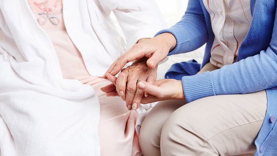 Frau hält Hand einer Seniorin