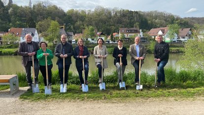 Alle Teilnehmer stehen in einer Reihe mit einem Spaten in der Hand